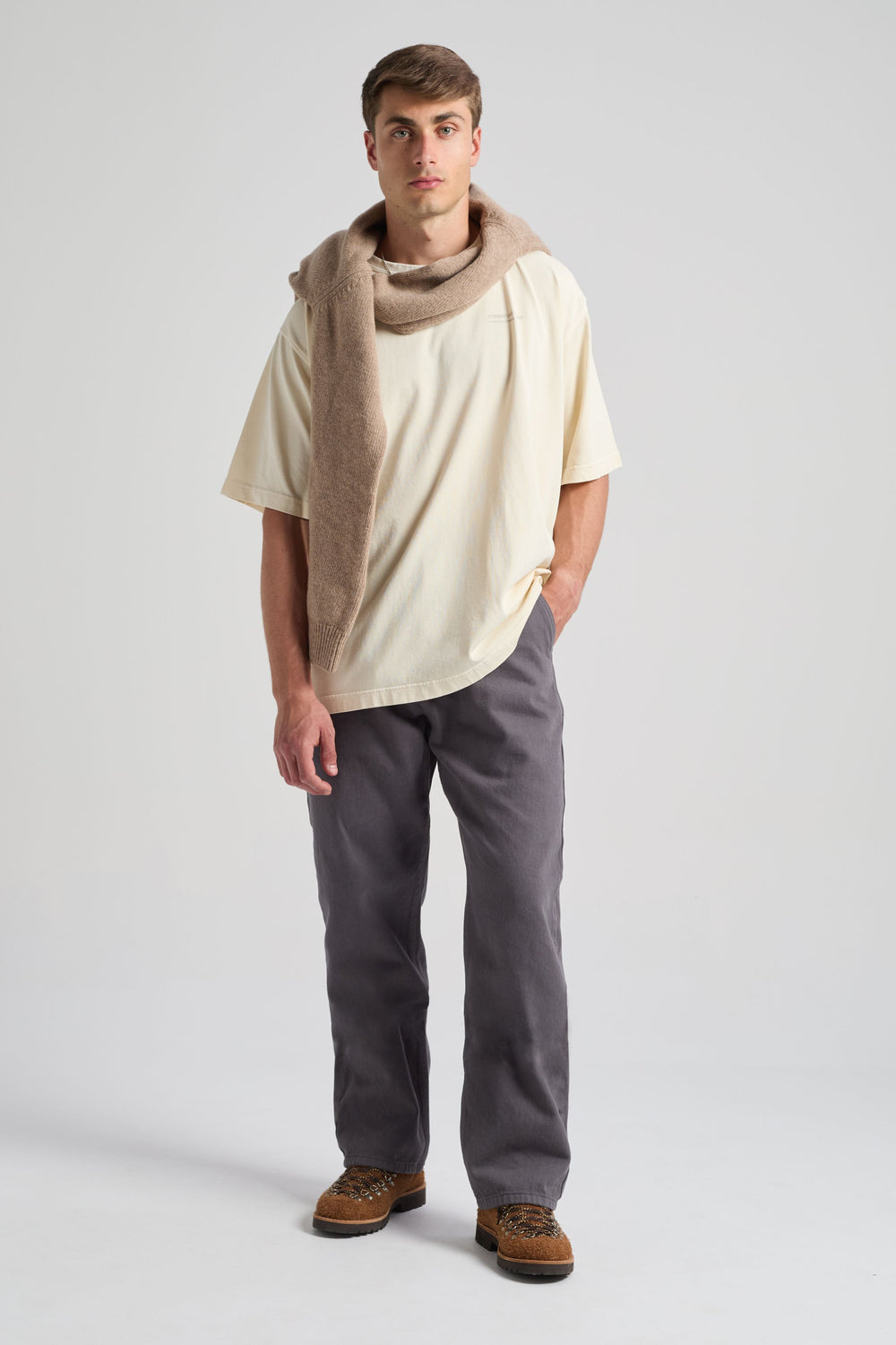 Persona che indossa una core oversized t-shirt color bianco sporco abbinata a pantaloni grigi e a una sciarpa marrone drappeggiata sulle spalle. | TP_IMAGE_TYPE=MODEL_FRONT