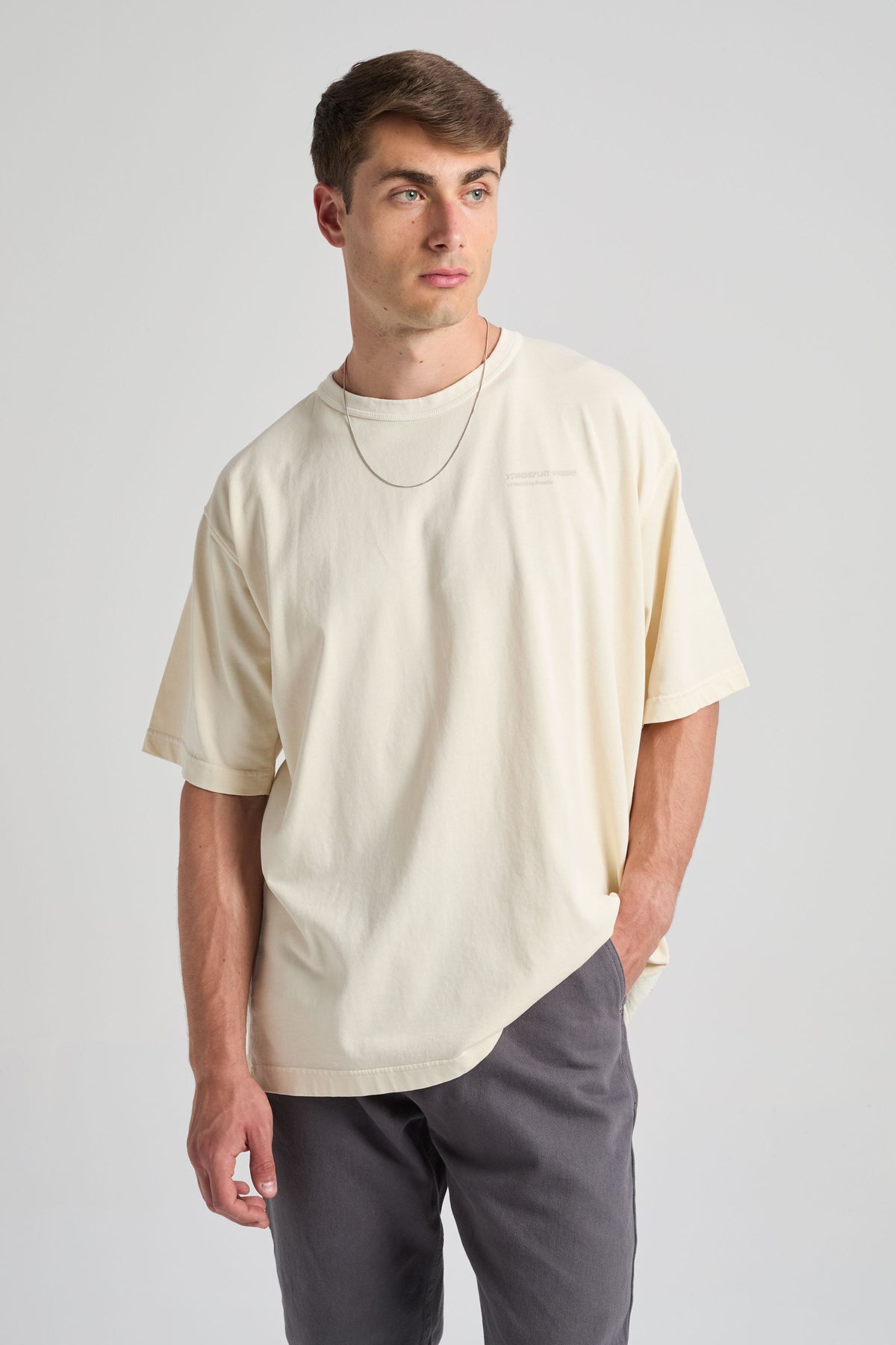 Personne portant un T-shirt oversize core en blanc cassé, associé à un pantalon décontracté, debout sur un fond neutre | TP_IMAGE_TYPE=MODEL_FRONT
