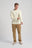 Personne portant un Flowers L/S T-Shirt en Antique White, avec un pantalon en velours côtelé et des chaussures décontractées, ajustant la manche, debout devant un fond clair. | TP_IMAGE_TYPE=MODEL_FRONT