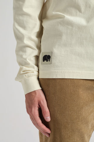 Persona che indossa una T-shirt Flowers L/S in Antique White, con dettaglio dell'etichetta sulla manica. | TP_IMAGE_TYPE=MODEL_FRONT