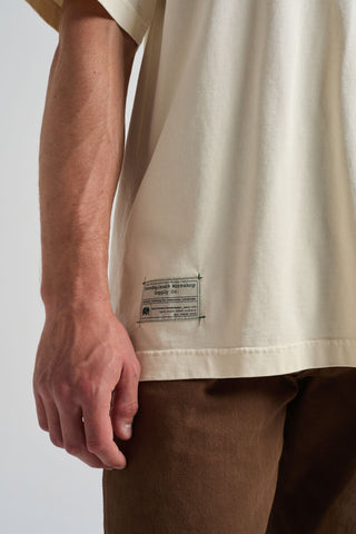 Personne portant un t-shirt oversize blanc antique avec un détail d'étiquette visible, associé à un pantalon marron | TP_IMAGE_TYPE=MODEL_FRONT