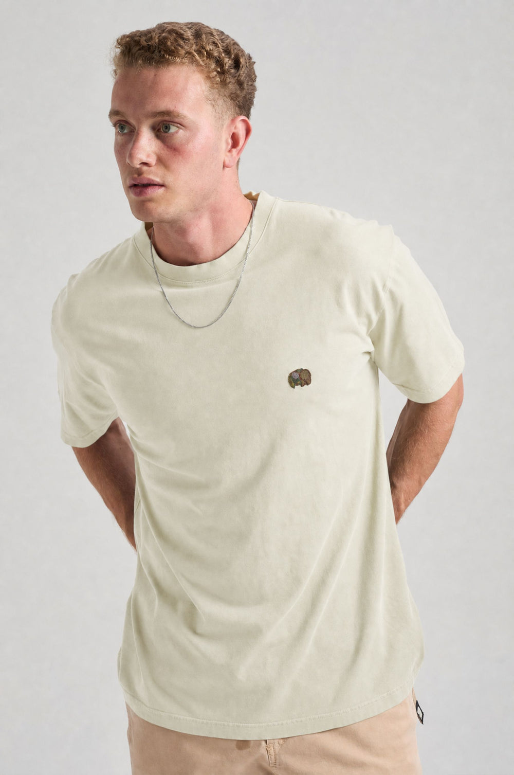Persona che indossa una Spring T-Shirt in Antique White, con un piccolo ricamo sul petto. | TP_IMAGE_TYPE=MODEL_FRONT