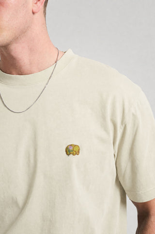 Persona che indossa una Spring T-Shirt in Antique White con un elefante ricamato sul petto. | TP_IMAGE_TYPE=MODEL_FRONT