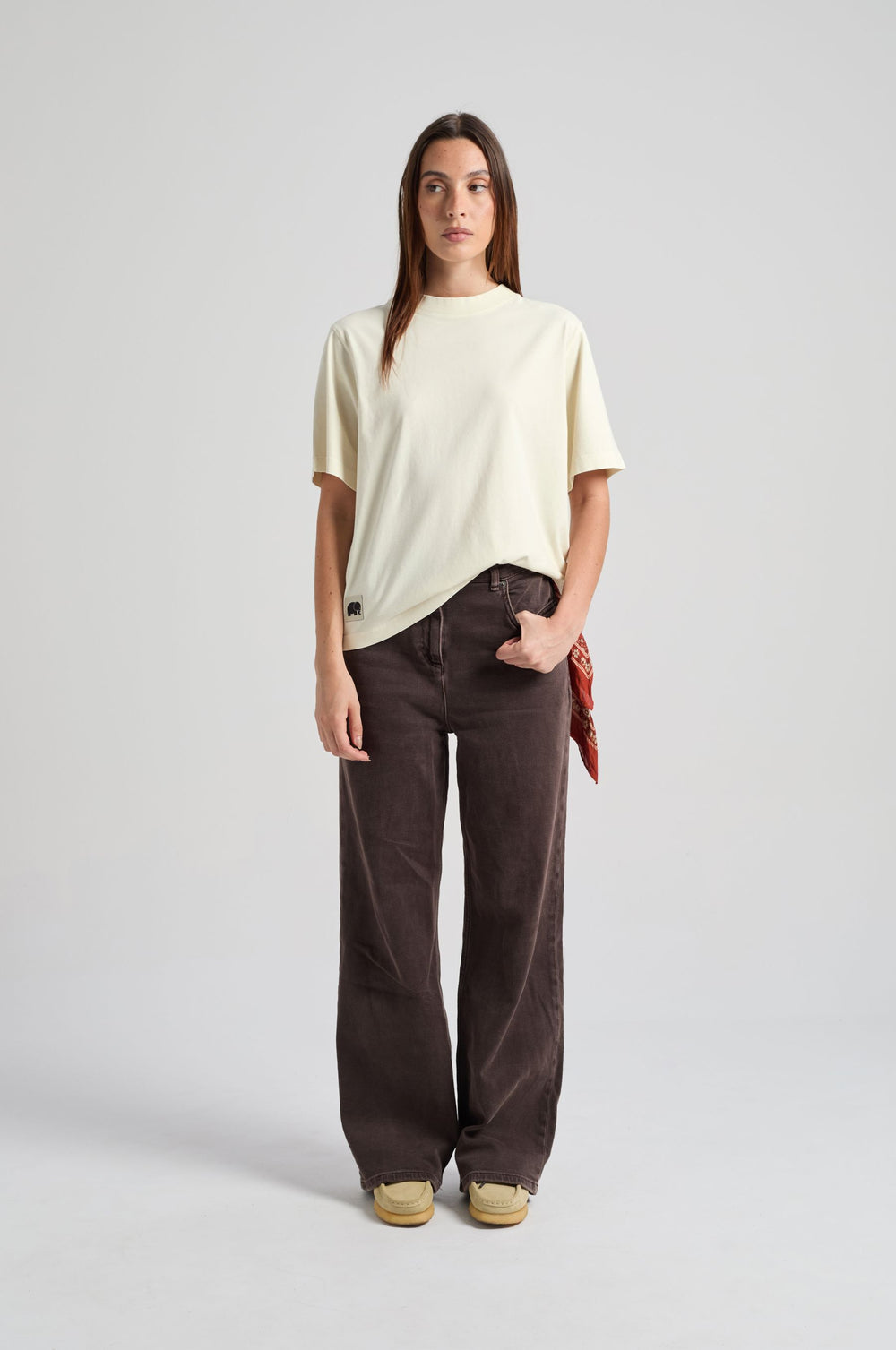 Personne portant le Women’s Amapola T-Shirt en Antique White, avec un pantalon ample et un bandana rouge noué à la taille, debout de face. | TP_IMAGE_TYPE=MODEL_FRONT