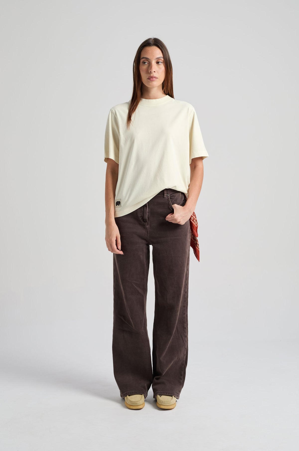 Personne portant le Women’s Amapola T-Shirt en Antique White, avec un pantalon ample et un bandana rouge noué à la taille, debout de face. | TP_IMAGE_TYPE=MODEL_FRONT