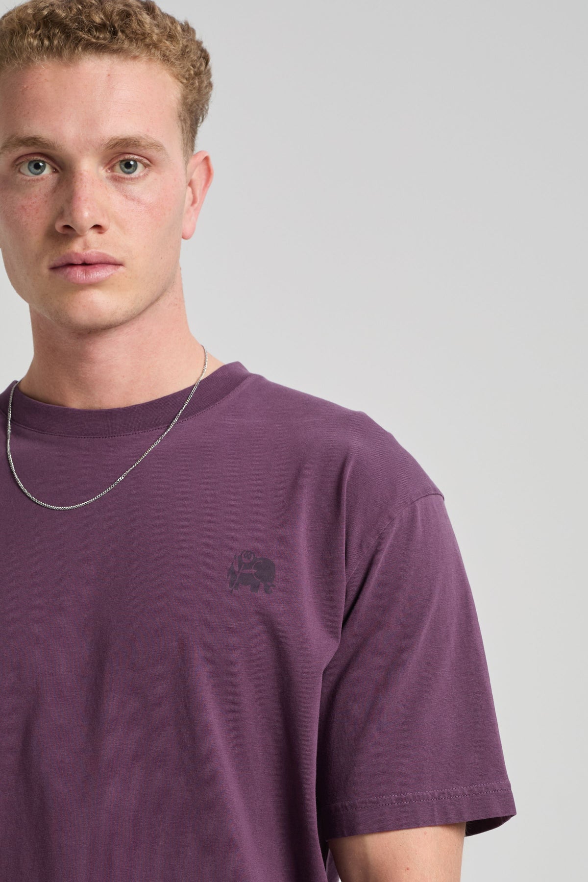 Person wearing a purple Bloom T-Shirt featuring a subtle logo on the chest | TP_IMAGE_TYPE=MODEL_FRONT
