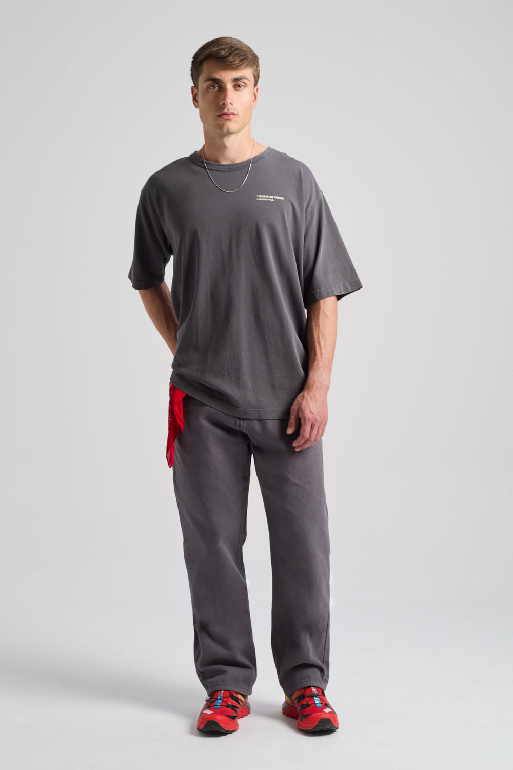 Persona che indossa una Core Oversized T-shirt in Forged Iron con vestibilità rilassata, abbinata a pantaloni coordinati e un accessorio rosso | TP_IMAGE_TYPE=MODEL_FRONT