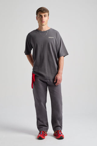 Persona che indossa una Core Oversized T-shirt in Forged Iron con vestibilità rilassata, abbinata a pantaloni coordinati e un accessorio rosso | TP_IMAGE_TYPE=MODEL_FRONT