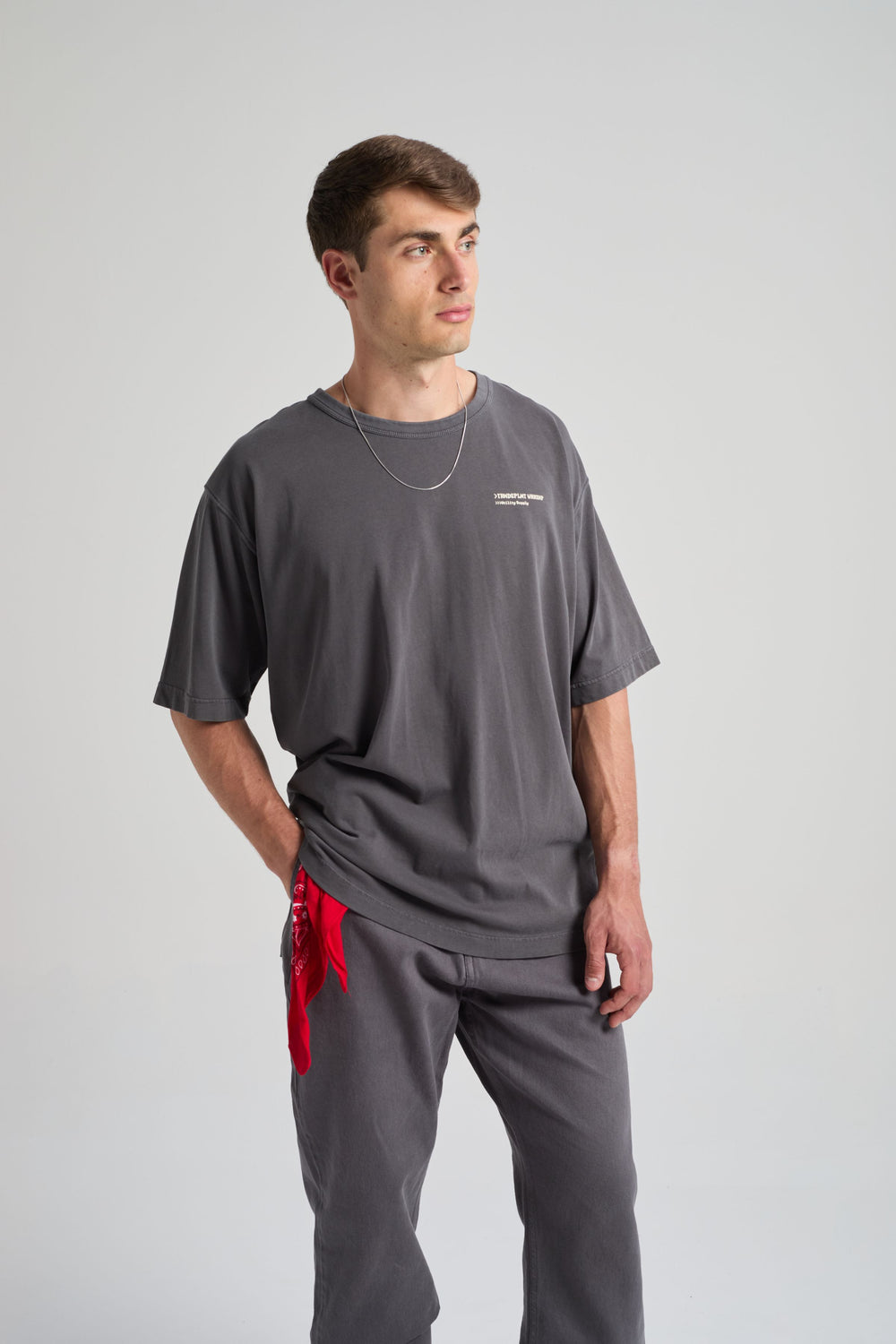 Persona che indossa una Core Oversized T-shirt in Forged Iron, abbinata a una catena argentata e a un bandana rosso. | TP_IMAGE_TYPE=MODEL_FRONT