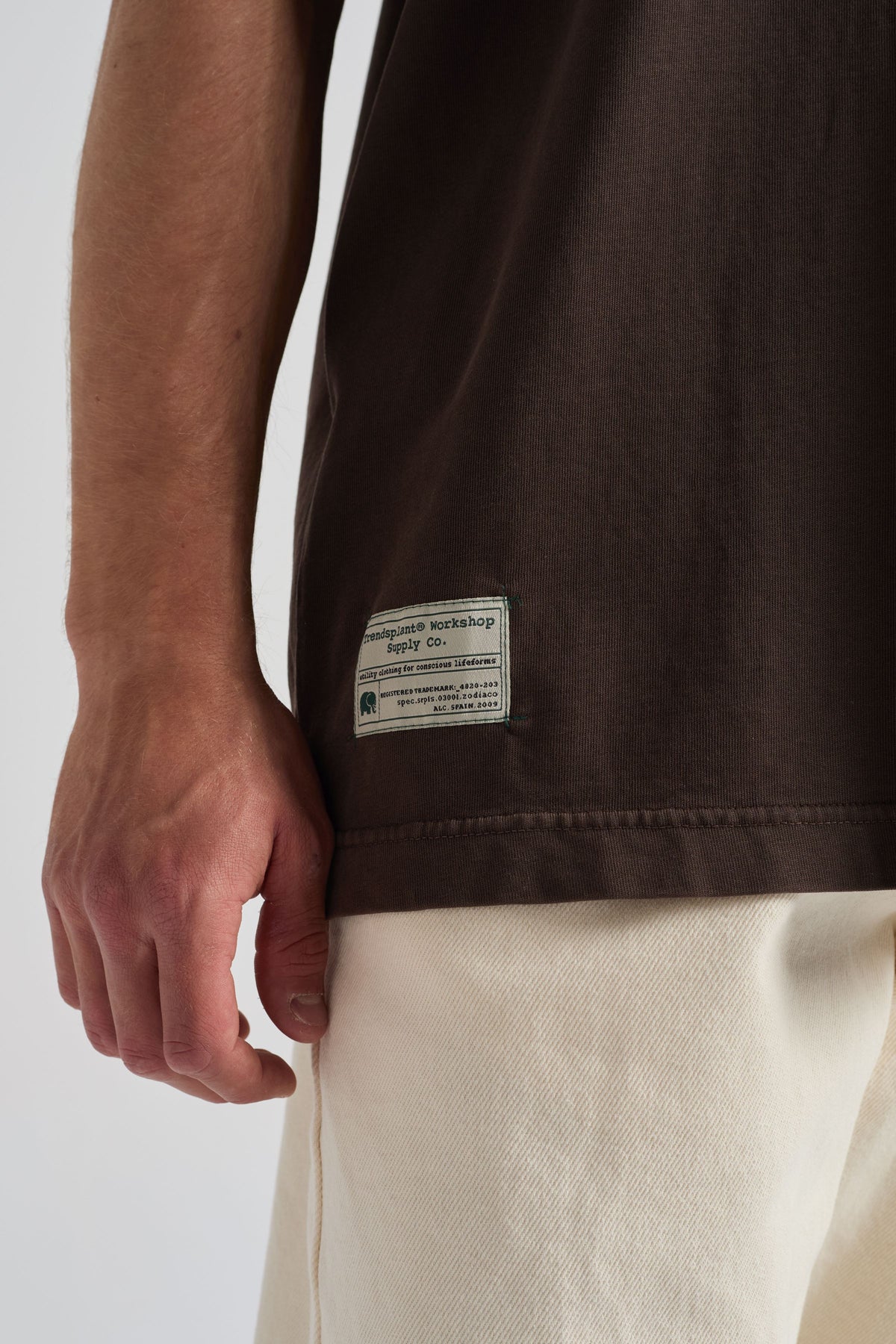 Persona che indossa una T-shirt Oversized marrone di Supply con dettaglio sull'etichetta, abbinata a un capo inferiore dai colori chiari | TP_IMAGE_TYPE=MODEL_FRONT