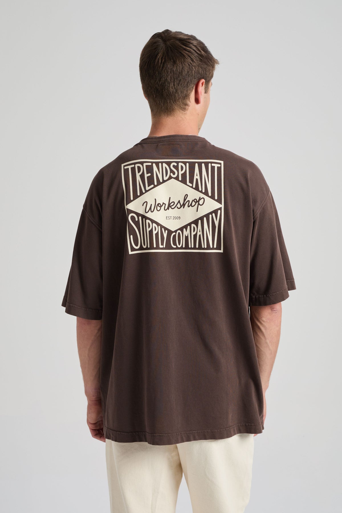 Persona che indossa la Supply Oversized T-shirt color Coffee Bean, vista posteriore con stampa grafica e vestibilità rilassata | TP_IMAGE_TYPE=MODEL_BACK