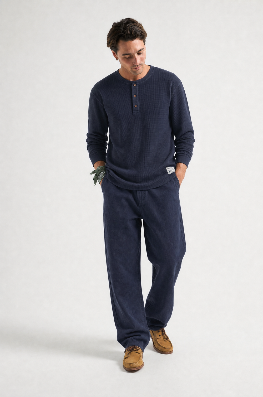 Persona che indossa una maglia henley a maniche lunghe blu navy e pantaloni della tuta blu navy abbinati, in piedi su uno sfondo da studio grigio chiaro. TP_IMAGE_TYPE=MODEL_FRONT