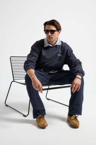 Personne portant The Garage Sweatshirt en Baritone Blue, en position assise avec des lunettes de soleil | TP_IMAGE_TYPE=MODEL_FRONT