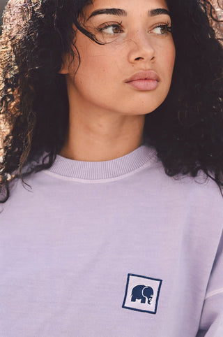Personne portant un sweat-shirt oversize lavande avec un logo éléphant sur la poitrine | TP_IMAGE_TYPE=MODEL_FRONT