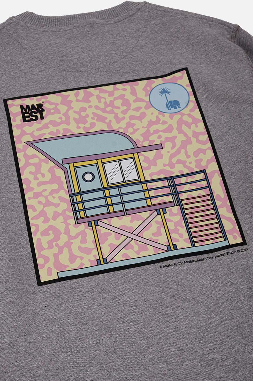 Dettaglio della felpa Antonyo Marest x Trendsplant Art Hut in Sport Grey con una vivace stampa grafica di una casa sulla spiaggia | TP_IMAGE_TYPE=DETAIL