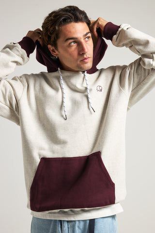 Persona che indossa la Hooded Oversized Sweatshirt in Warm Heather Grey e Wine Red, con vista frontale che mette in risalto il dettaglio della felpa con cappuccio e della tasca a marsupio. | TP_IMAGE_TYPE=MODEL_FRONT