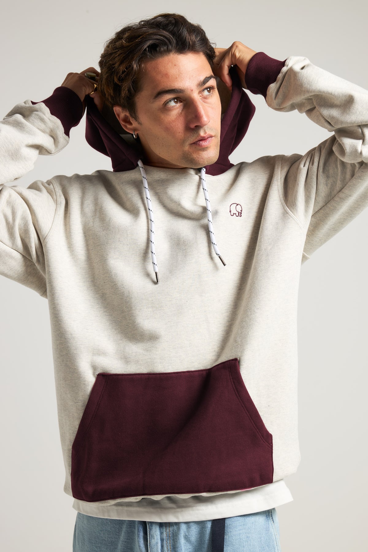 Persona che indossa la Hooded Oversized Sweatshirt in Warm Heather Grey e Wine Red, con vista frontale che mette in risalto il dettaglio della felpa con cappuccio e della tasca a marsupio. | TP_IMAGE_TYPE=MODEL_FRONT