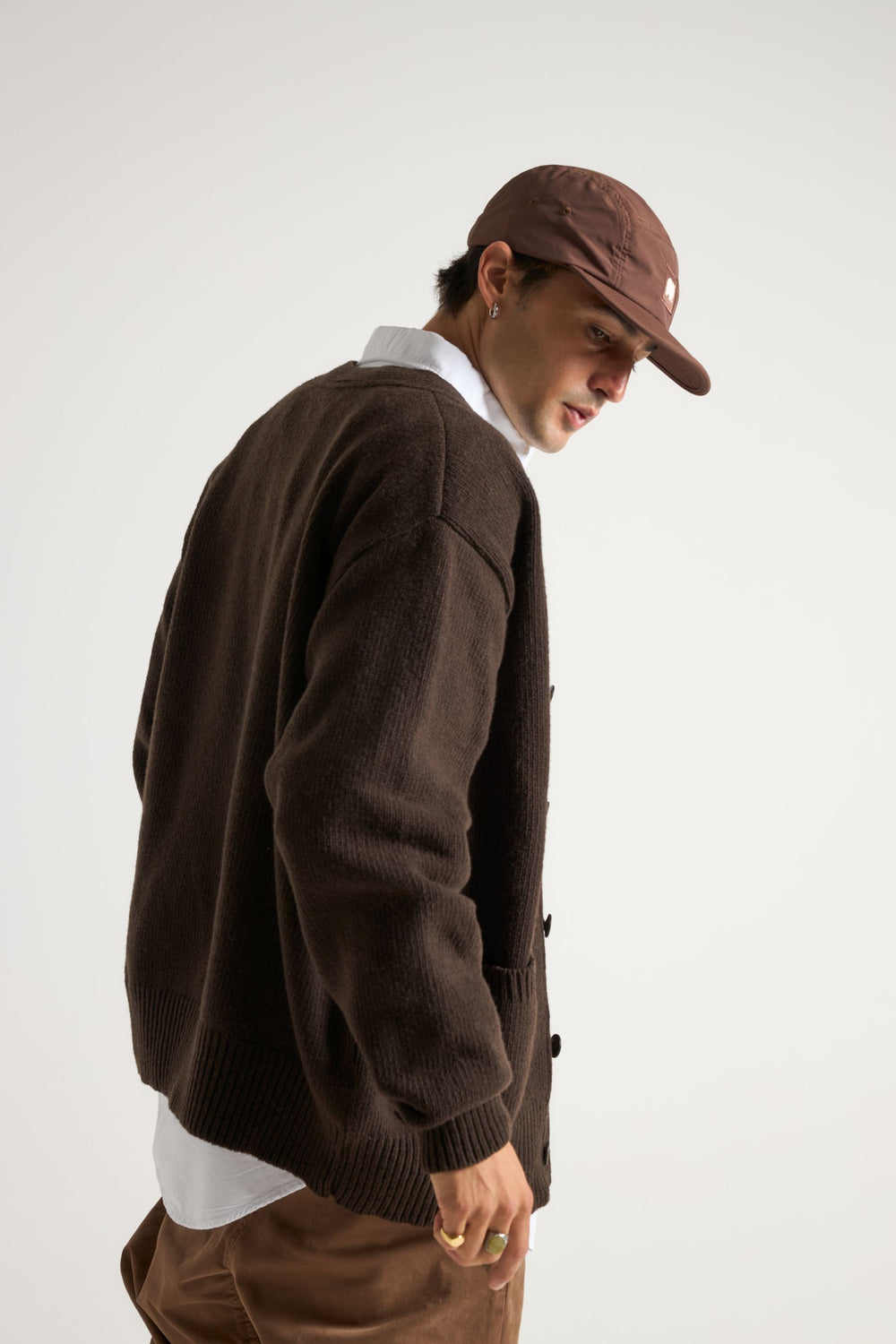 Persona che indossa un cardigan Relleu color cioccolato, abbinato a una camicia bianca e a un berretto marrone, ripresa di spalle. | TP_IMAGE_TYPE=MODEL_BACK