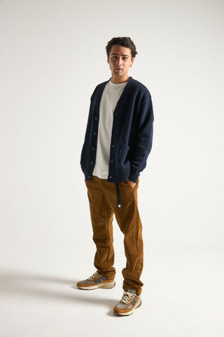 Personne portant un cardigan Relleu bleu marine foncé sur un t-shirt blanc, associé à un pantalon en velours côtelé marron et des baskets, en pose dans un studio. | TP_IMAGE_TYPE=MODEL_FRONT