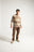 Persona che indossa il Sella Knit in Latte/Nomad Brown, abbinato a pantaloni e sneakers marroni coordinati, in posa in uno studio fotografico. | TP_IMAGE_TYPE=MODEL_FRONT