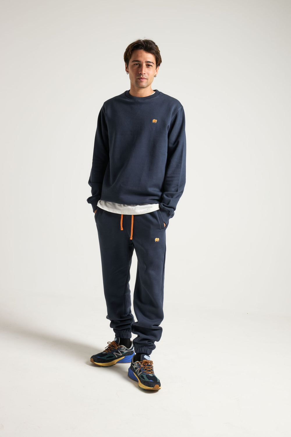 Personne portant un Organic Essential Sweatshirt en coloris Trendsplant Blue, les mains dans les poches, sur un fond uni. | TP_IMAGE_TYPE=MODEL_FRONT