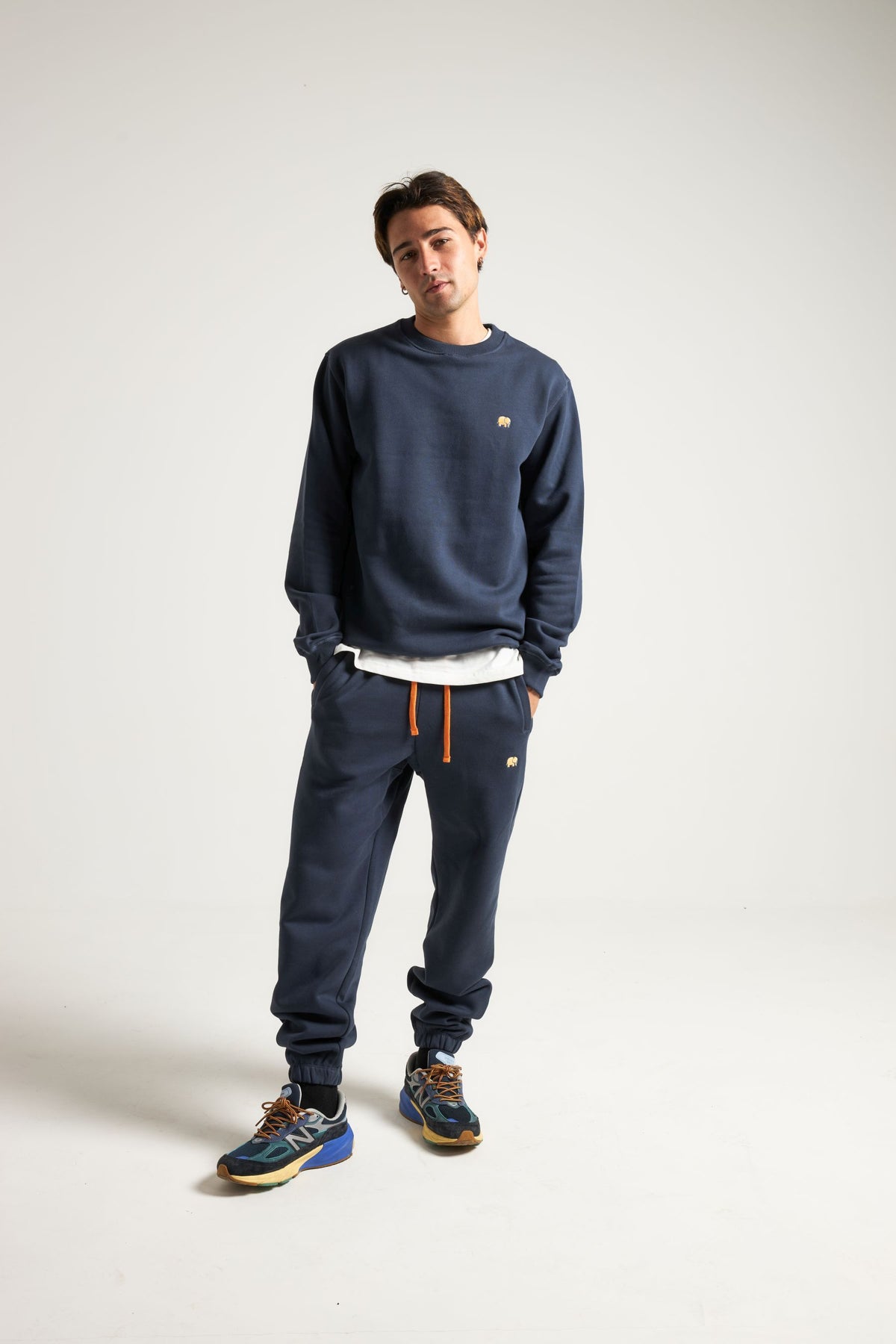 Persona che indossa Organic Essential Sweatpants in Trendsplant Blue, abbinati a una felpa coordinata e scarpe sportive | TP_IMAGE_TYPE=MODEL_FRONT