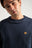 Personne portant un Organic Essential Sweatshirt bleu avec un logo éléphant brodé. | TP_IMAGE_TYPE=MODEL_FRONT