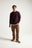 Persona che indossa un maglione in maglia bordeaux dalla vestibilità casual, abbinato a pantaloni marroni e sneakers, in piedi su uno sfondo neutro | TP_IMAGE_TYPE=MODEL_FRONT
