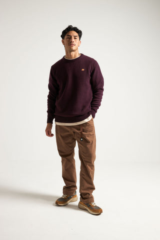Persona che indossa un maglione in maglia bordeaux dalla vestibilità casual, abbinato a pantaloni marroni e sneakers, in piedi su uno sfondo neutro | TP_IMAGE_TYPE=MODEL_FRONT