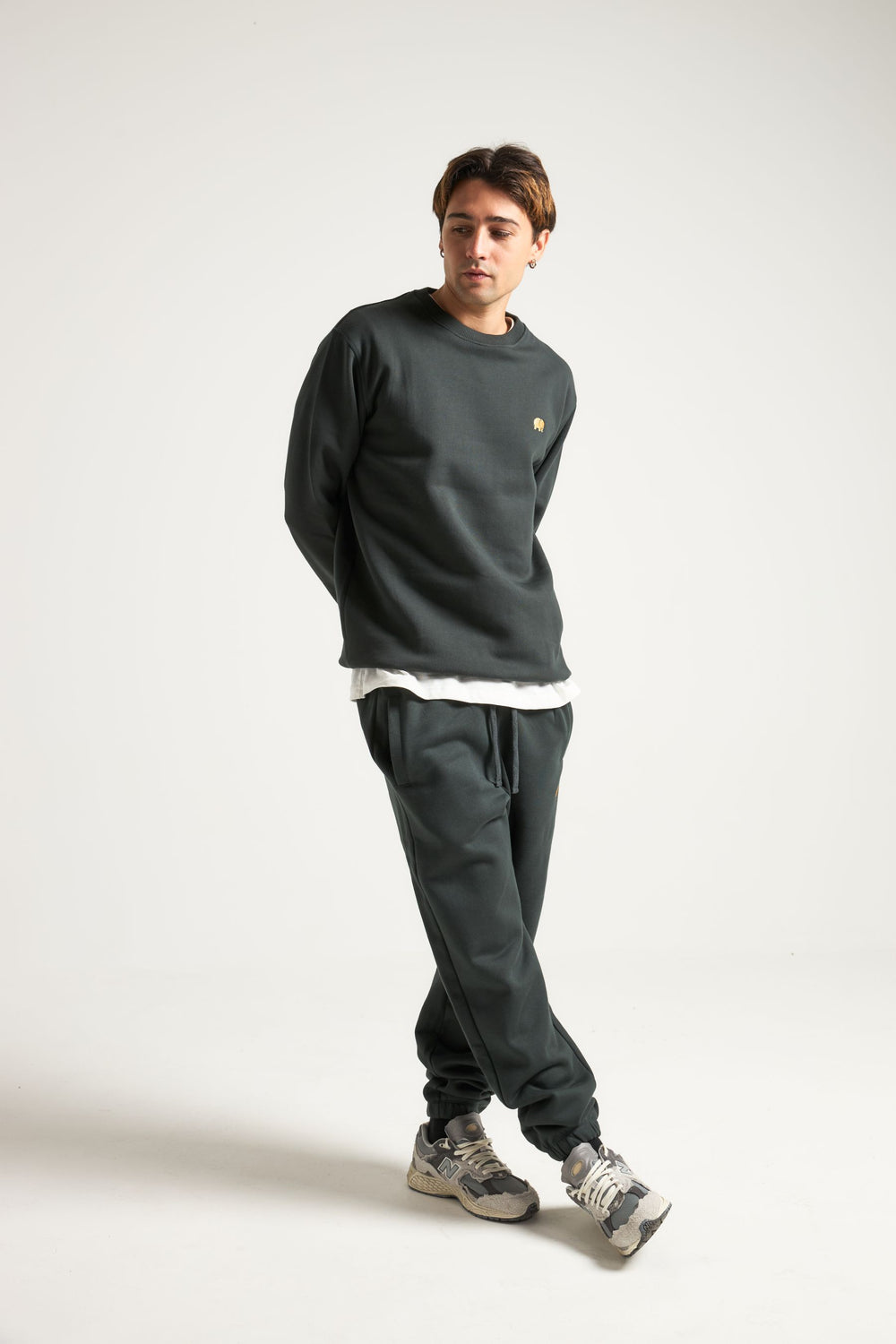 Personne portant un Organic Essential Sweatshirt en Scarab Green, associé à un pantalon assorti, dans une pose décontractée | TP_IMAGE_TYPE=MODEL_FRONT