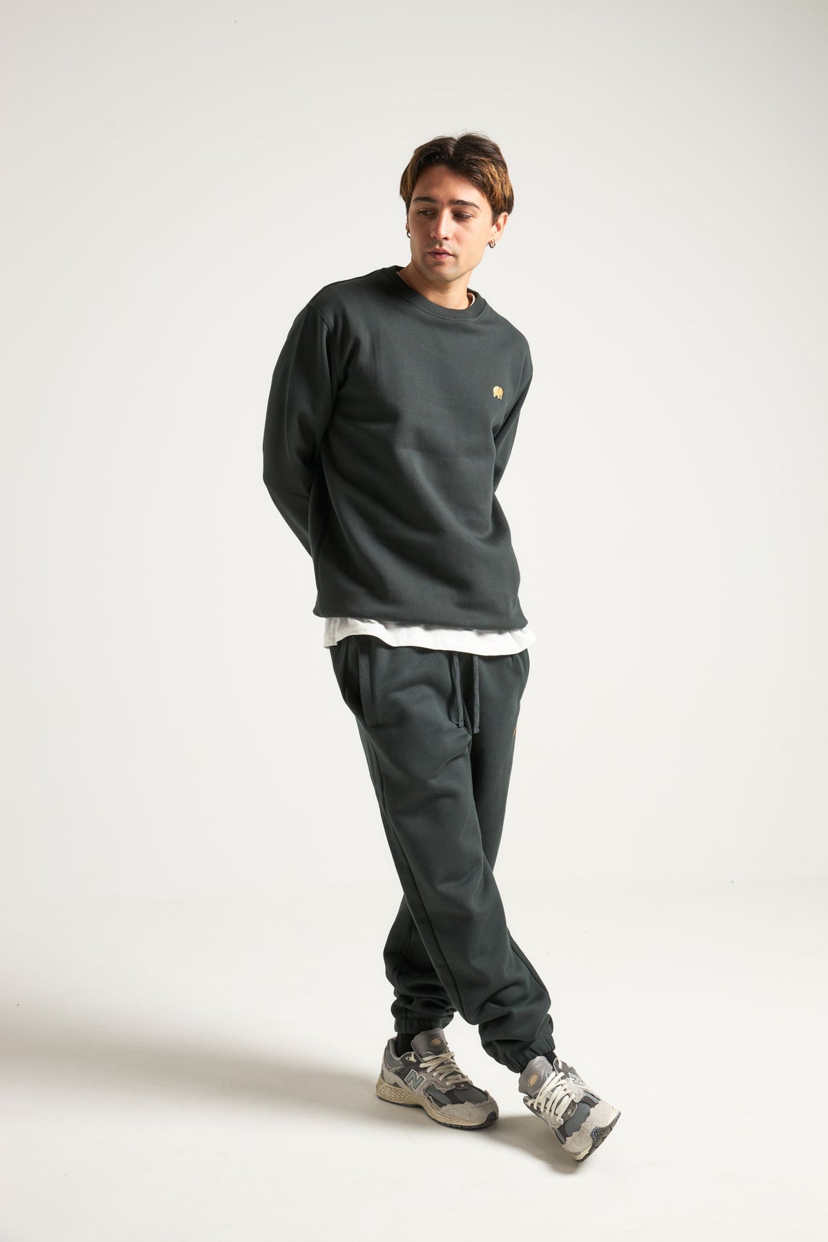 Personne portant un Organic Essential Sweatshirt en Scarab Green, associé à un pantalon assorti, dans une pose décontractée | TP_IMAGE_TYPE=MODEL_FRONT