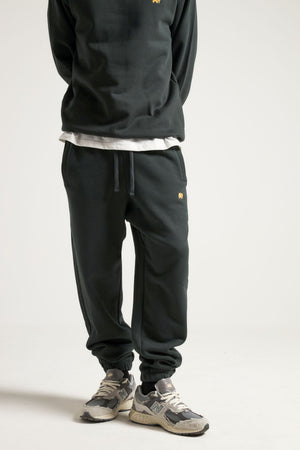 Persona che indossa Organic Essential Sweatpants in Scarab Green, con una vestibilità comoda ed elegante e chiusura con coulisse. | TP_IMAGE_TYPE=MODEL_FRONT