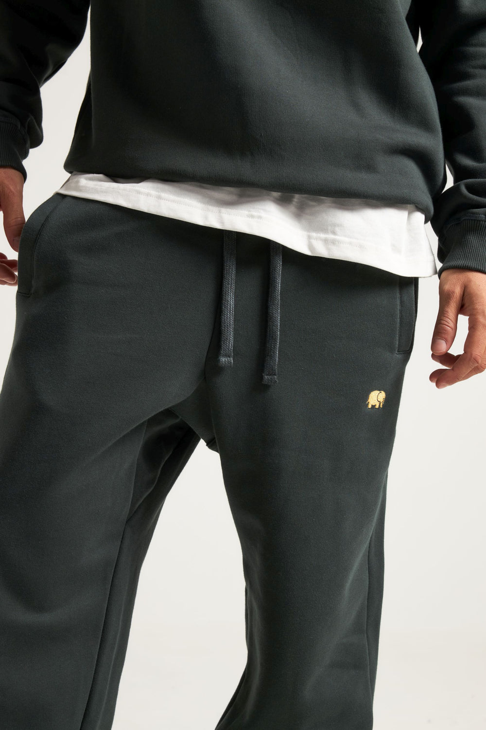 Persona che indossa gli Organic Essential Sweatpants in Scarab Green, abbinati a una camicia bianca e a un top coordinato. | TP_IMAGE_TYPE=MODEL_FRONT