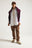 Persona che indossa una Postiguet Pigment Dyed Twill Shirt in Bright White, abbinata a pantaloni marroni e a un maglione bordeaux drappeggiato sulle spalle | TP_IMAGE_TYPE=MODEL_FRONT