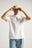 Persona che indossa una t-shirt essenziale biologica in colore naturale, abbinata a un cappellino e jeans blu casual | TP_IMAGE_TYPE=MODEL_FRONT