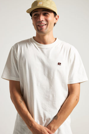 Persona che indossa una t-shirt essenziale biologica in colore naturale, con un piccolo ricamo grafico sul petto | TP_IMAGE_TYPE=MODEL_FRONT