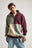 Person wearing a color block quarter zip sweatshirt in shades of iron veil, featuring a mix of maroon, light green, and beige panels. | TP_IMAGE_TYPE=MODEL_FRONT