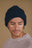 Personne portant un Campana Cuff Beanie en marine, regardant vers le bas avec un sourire doux, dans un style décontracté. | TP_IMAGE_TYPE=MODEL_FRONT