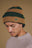 Personne portant le bonnet Montcabrer dans les coloris Emmerald et Dune, avec rayures horizontales et un logo éléphant brodé. | TP_IMAGE_TYPE=MODEL_FRONT