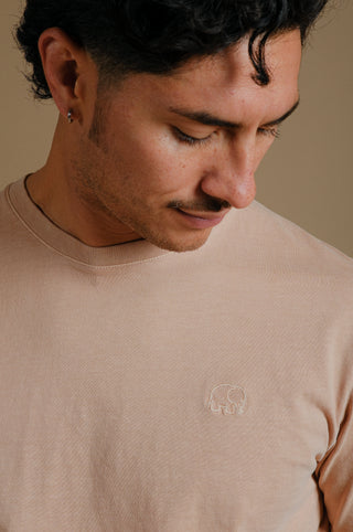 Personne portant un Essential Pigment T-Shirt en Cuban Sand, regardant vers le bas avec un logo brodé visible | TP_IMAGE_TYPE=MODEL_FRONT