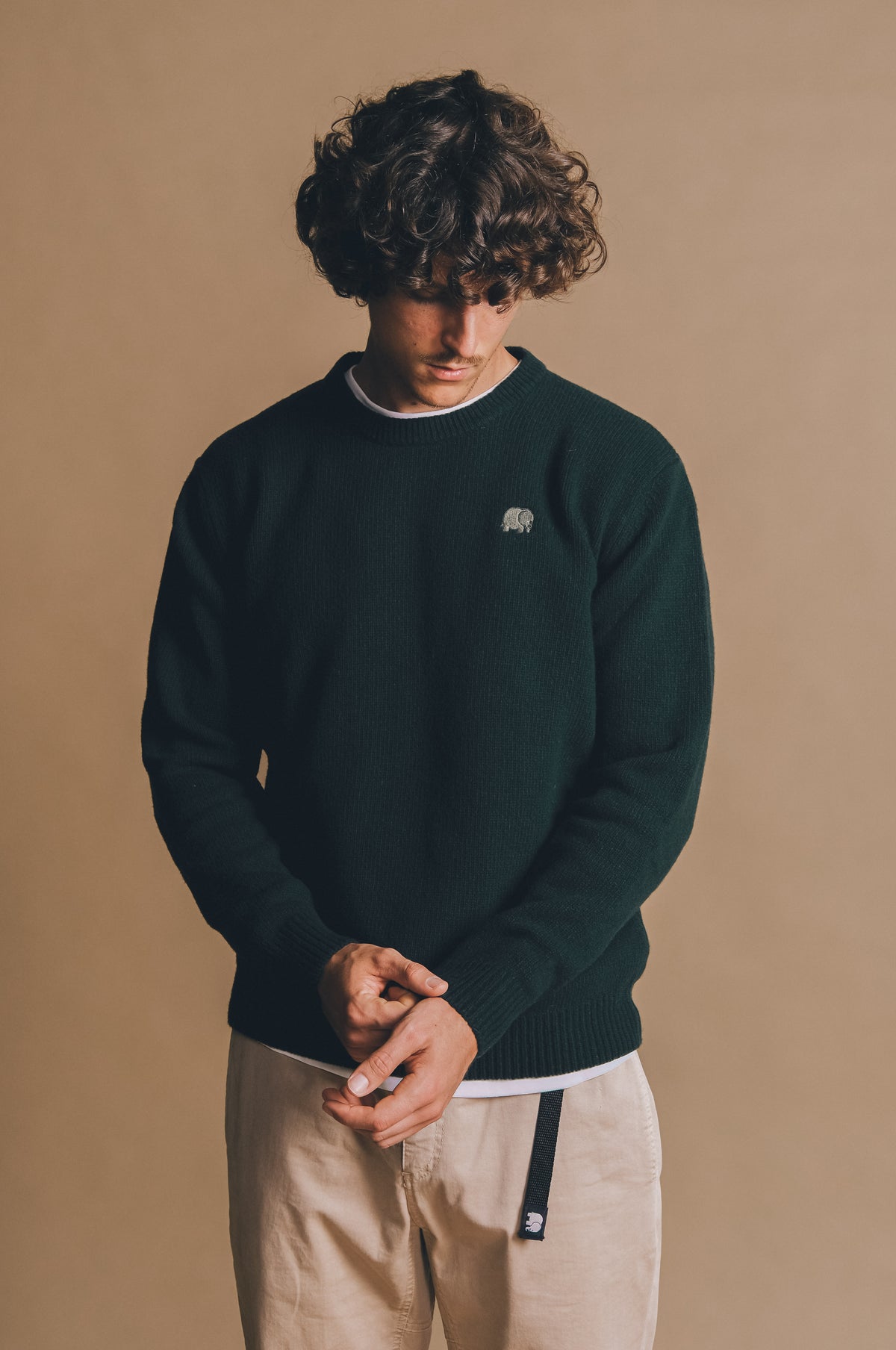 Persona che indossa un maglione Sella Knit verde pino con texture a coste, abbinato a pantaloni chiari, su uno sfondo neutro. | TP_IMAGE_TYPE=MODEL_FRONT