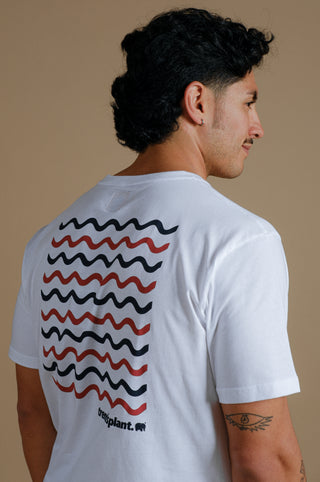 Persona che indossa una t-shirt biologica bianca con un motivo grafico a onda, vista posteriore | TP_IMAGE_TYPE=MODEL_BACK