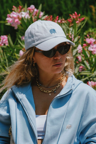 Persona che indossa un Logo Dad Cap Sky Blue con sfondo floreale | TP_IMAGE_TYPE=LIFESTYLE