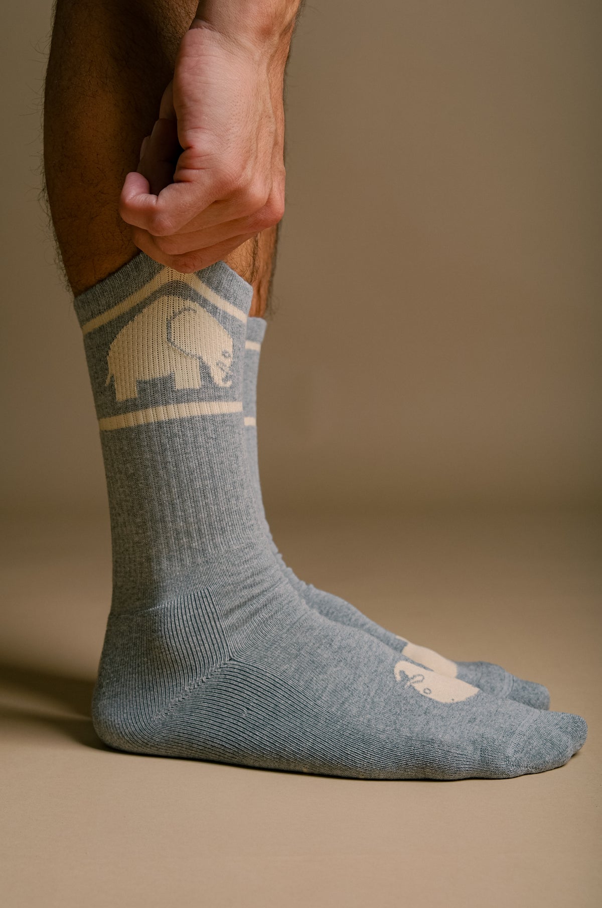 Person wearing grey organic cotton athletic socks, adjusting the sock | TP_IMAGE_TYPE=MODEL_FRONT