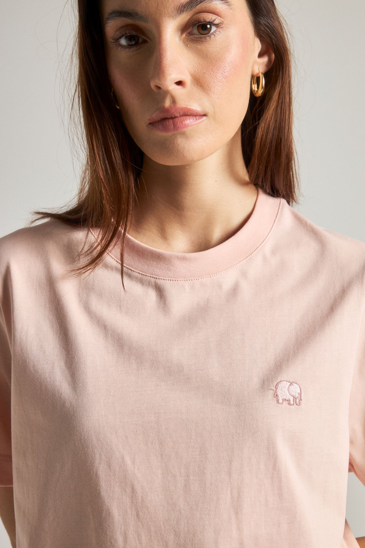 Personne portant un Pale Pink Organic Essential T-Shirt avec un éléphant brodé, vue de face | TP_IMAGE_TYPE=MODEL_FRONT
