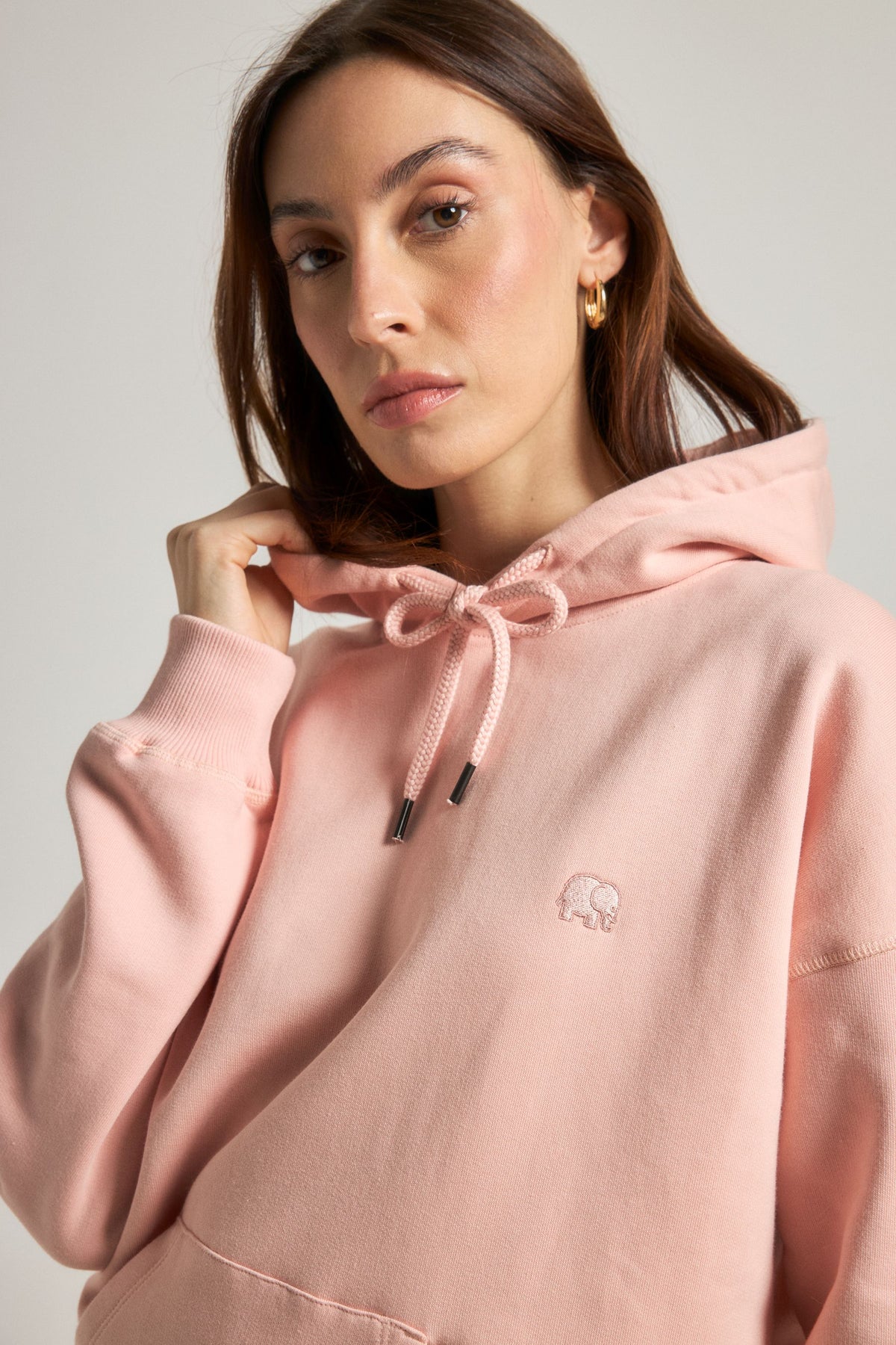 Persona che indossa una felpa oversize rosa pallido con coulisse e patch con logo | TP_IMAGE_TYPE=MODEL_FRONT