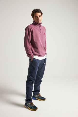 Personne portant un Sauce Pigment Dyed Quarter Zip Sweatshirt en Garnacha Red, associé à un pantalon bleu marine et des chaussures de sport | TP_IMAGE_TYPE=MODEL_FRONT