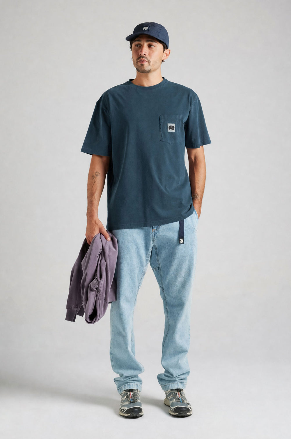 Persona che indossa la t-shirt Garza Moonlit Ocean, tiene in mano un maglione viola con jeans azzurri e sneakers. | TP_IMAGE_TYPE=MODEL_FRONT