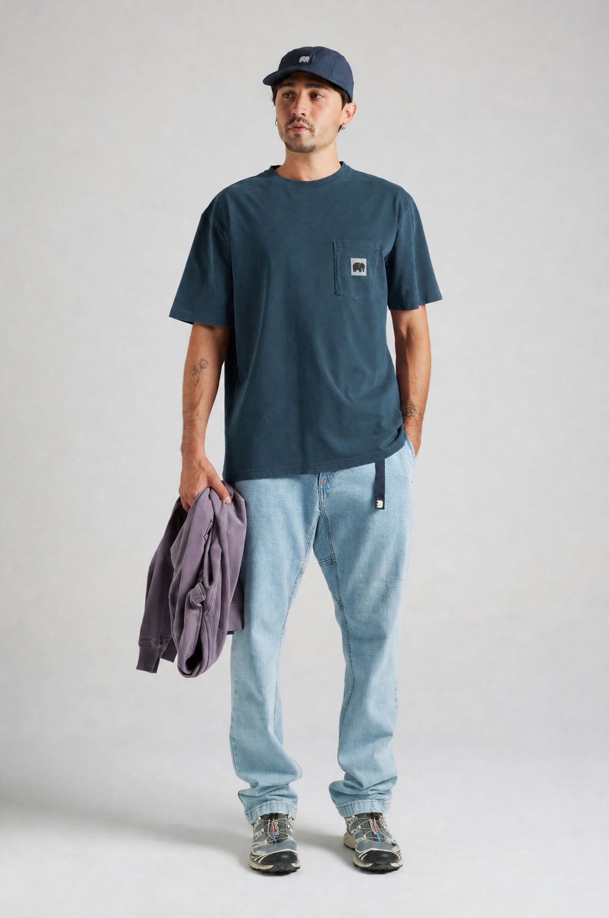 Persona che indossa la t-shirt Garza Moonlit Ocean, tiene in mano un maglione viola con jeans azzurri e sneakers. | TP_IMAGE_TYPE=MODEL_FRONT