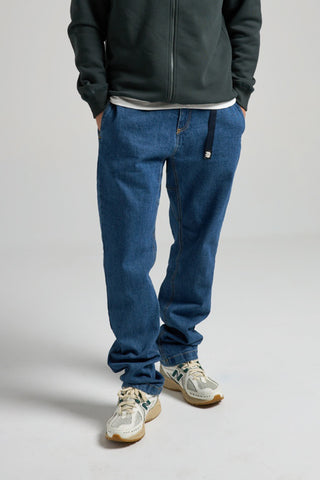 Persona che indossa Climber Pant in denim riciclato, lavaggio medium, abbinati a una felpa scura e sneakers | TP_IMAGE_TYPE=MODEL_FRONT